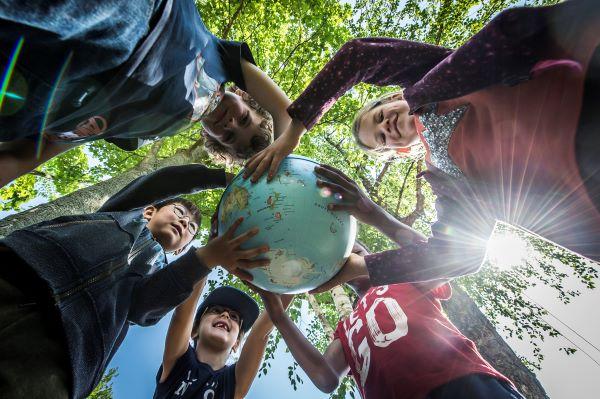Kinderen in kring met wereldbol in het midden.